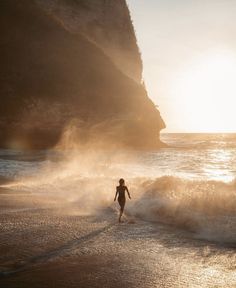 a person running on the beach at sunset with waves crashing in front of their feet