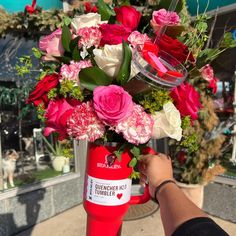 a person holding a red and white vase filled with flowers