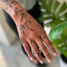 a person with tattoos on their arm and hand next to a potted green plant