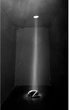 a black and white photo of a light coming from the ceiling in an empty room