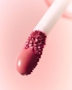 a close up view of a pink lipstick with the top lip partially covered by a white tube