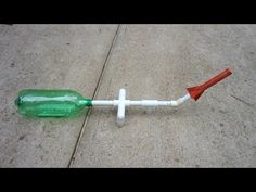 a green and white plastic toothbrush laying on the ground next to a cement sidewalk