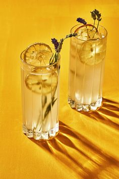 two glasses filled with lemonade and lavender sprigs on a yellow tablecloth