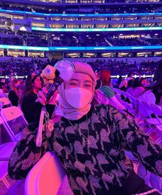 a woman wearing a face mask and sitting in a chair at an event with other people