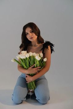 a woman sitting on the ground holding a bouquet of flowers