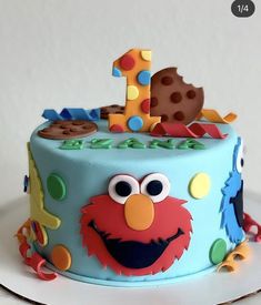 a blue birthday cake with an elmo face and number one frosting on top