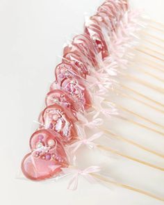 pink heart shaped lollipops are lined up on sticks