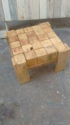 a small wooden table made out of wood blocks on the ground with no one around it