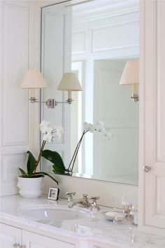 a bathroom with a sink, mirror and two lights on the wall next to it