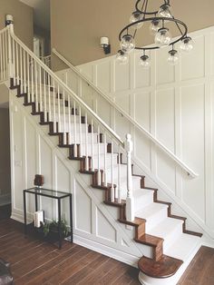 a white staircase with wood steps and glass chandelier in a living room area