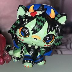 a green and black cat figurine next to a red heart