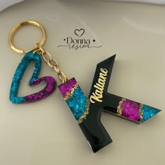 the letter k is made out of glitter and has a key chain attached to it