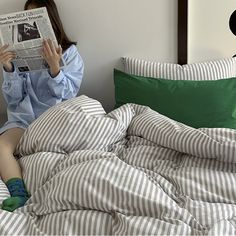 a woman reading a newspaper while sitting in bed