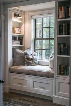 a window seat in the corner of a room with bookshelves and pillows on it