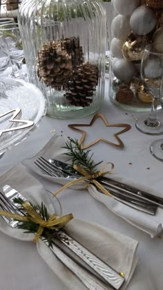 the table is set with silverware and pine cones