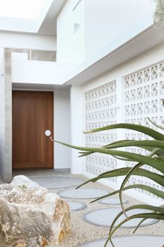 the entrance to a modern house with large rocks and plants in front of it's door