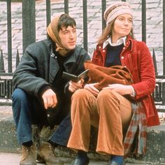 a young man and woman sitting on the sidewalk