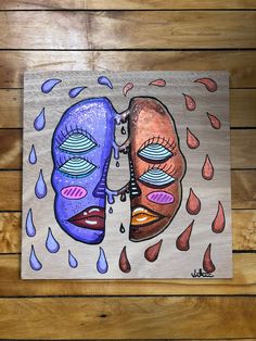 two faces are painted on wood with water drops coming out of the top and bottom