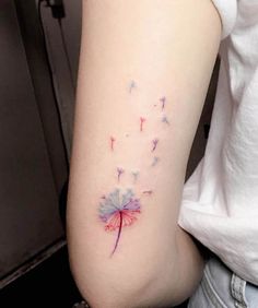 a woman's arm with a dandelion tattoo on the left side of her arm