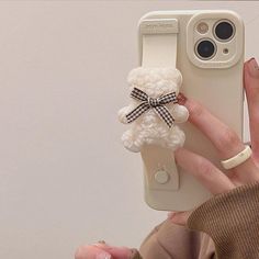 a person holding up a cell phone case with a crocheted bow on it