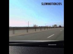 a car driving down a highway next to a fence and road sign with the word slowmoton on it