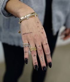 a woman's hand with tattoos and rings on it