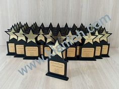 five star shaped trophies with gold and black trimmings on each one, all lined up in a row