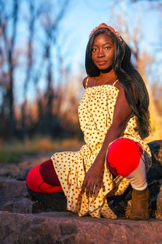 a woman sitting on top of a rock next to trees