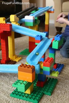 a child playing with legos on the floor in front of a toy train track