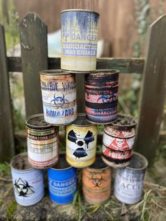 several tins are stacked on top of each other in front of a wooden fence