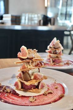 two white plates topped with food on top of a wooden table next to a bar