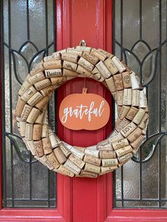 a wreath made out of wine corks with the word grateful written on it in front of a red door