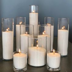 a group of white candles sitting on top of a table next to eachother