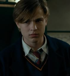 a young man in a suit and tie looking at the camera with serious expression on his face