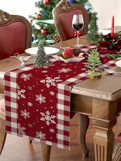 a dining room table set for christmas with red and white plaid cloth on the table