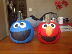 two decorated pumpkins sitting on top of a wooden table