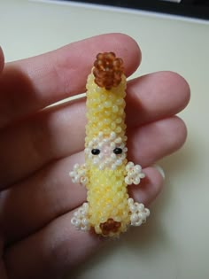 a person holding a tiny beaded object in their hand