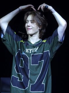 a young man with his hands on his head and wearing a jersey that says kyn