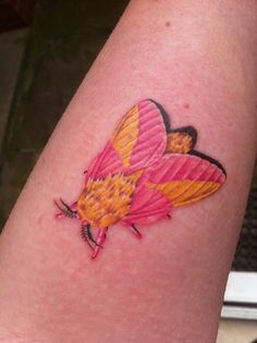 a small pink butterfly tattoo on the left arm and right leg, with yellow wings