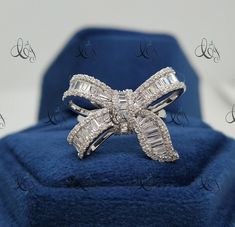 a diamond bow ring sitting on top of a blue velvet box