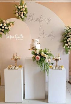 three white pedestals with flowers and candles on them in front of a wedding sign