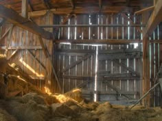 an open barn door with hay in the foreground and sunlight coming through it on top