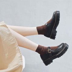 a woman sitting on top of a white chair wearing black shoes and socks with brown socks