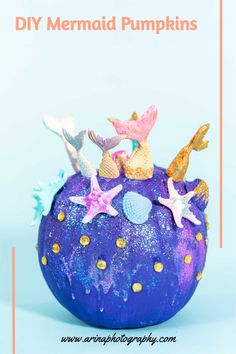 a purple ball with gold stars and mermaids on it, sitting in front of a blue background