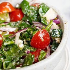 a close up of a salad in a bowl with tomatoes, onions and lettuce