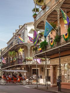 a horse drawn carriage driving down a street next to tall buildings with balconies