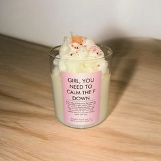 a small glass cup with whipped cream and sprinkles in it on a wooden table