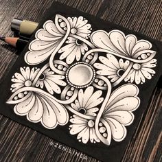 a black and white drawing of flowers on a piece of paper next to a pencil