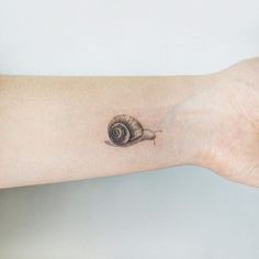 a small snail tattoo on the wrist