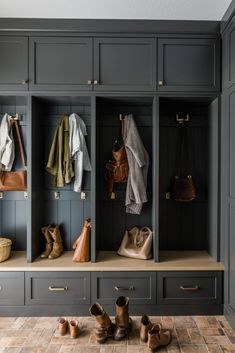 an organized mud room with gray cabinets and wooden shoes on the floor, purses and coats hanging from hooks